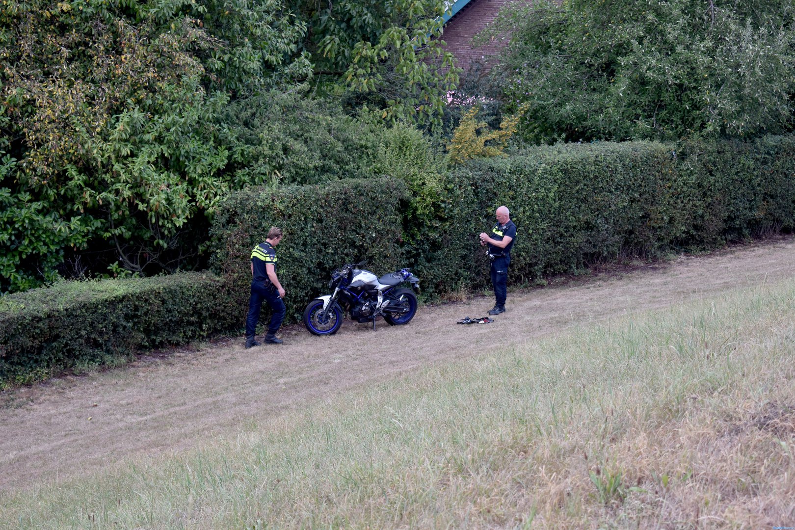 Motorrijder valt op dijk, motor schuift naar beneden