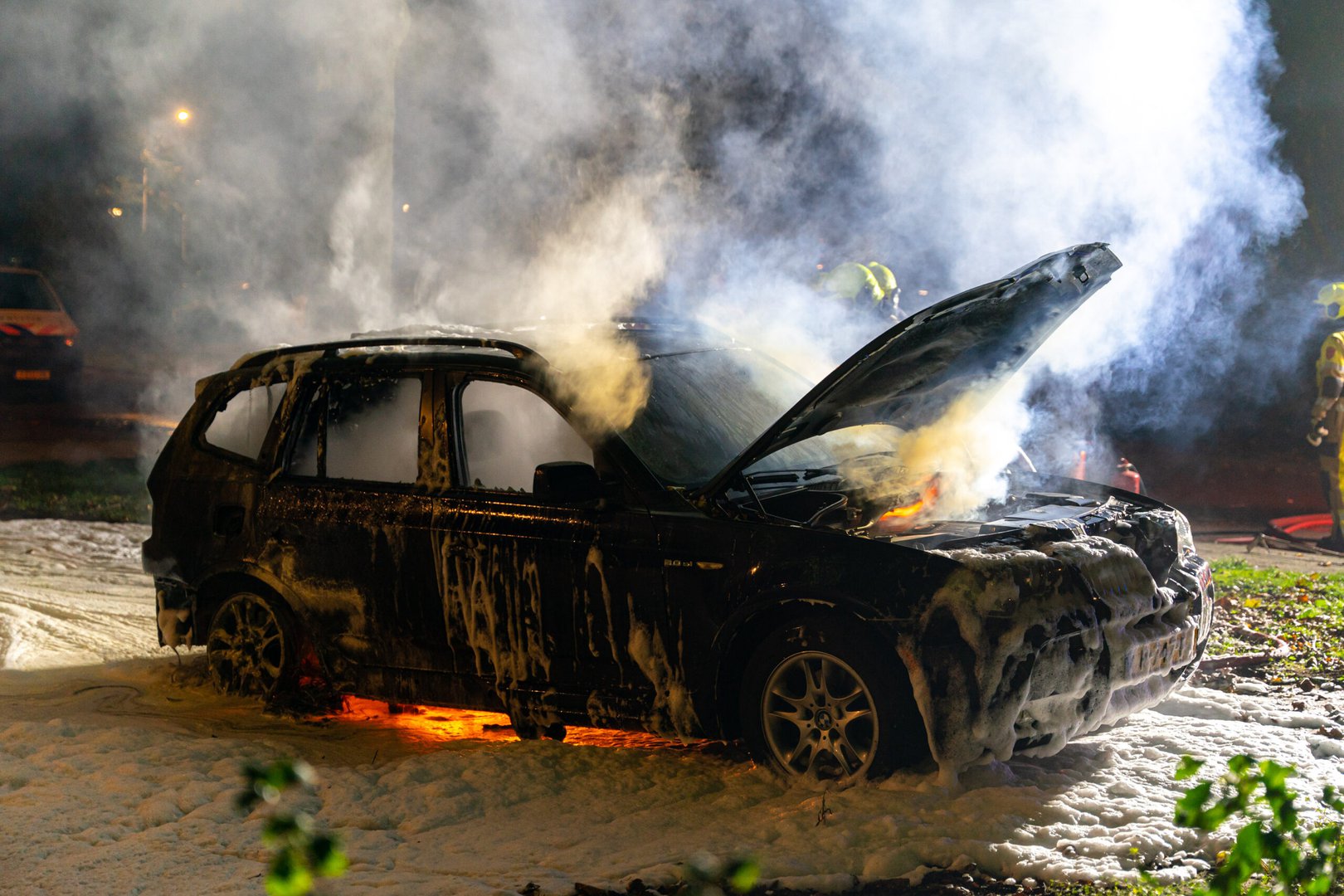 Brandweer blust in brand gestoken auto