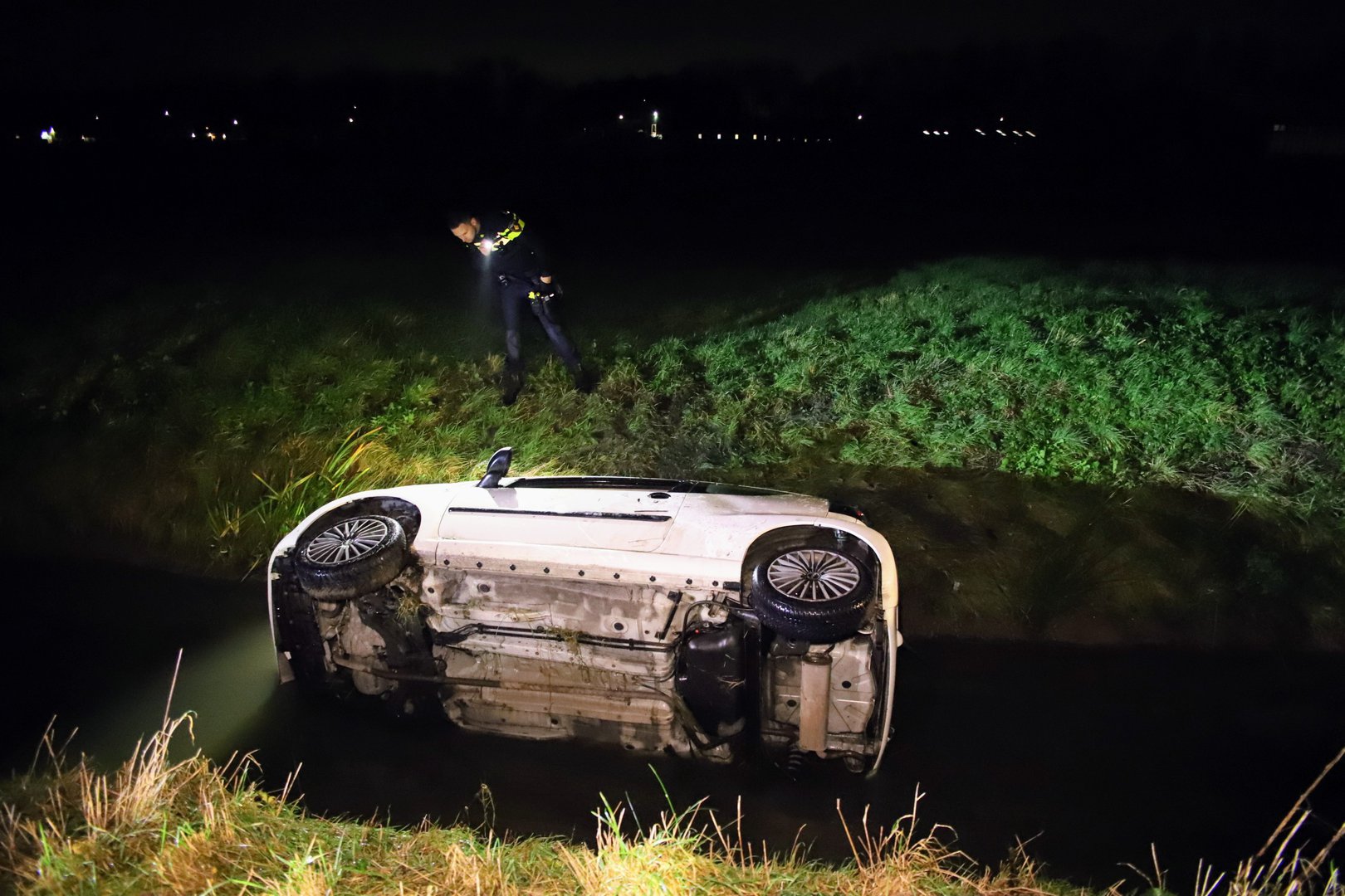 Auto op z’n kant in sloot, inzittenden met schrik vrij