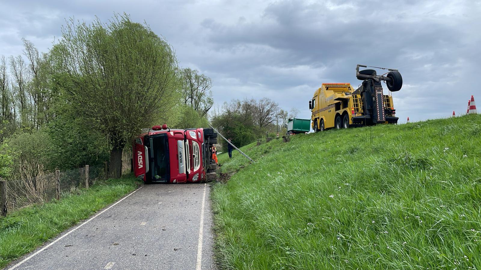 Vrachtwagen rolt van dijk, chauffeur ongedeerd