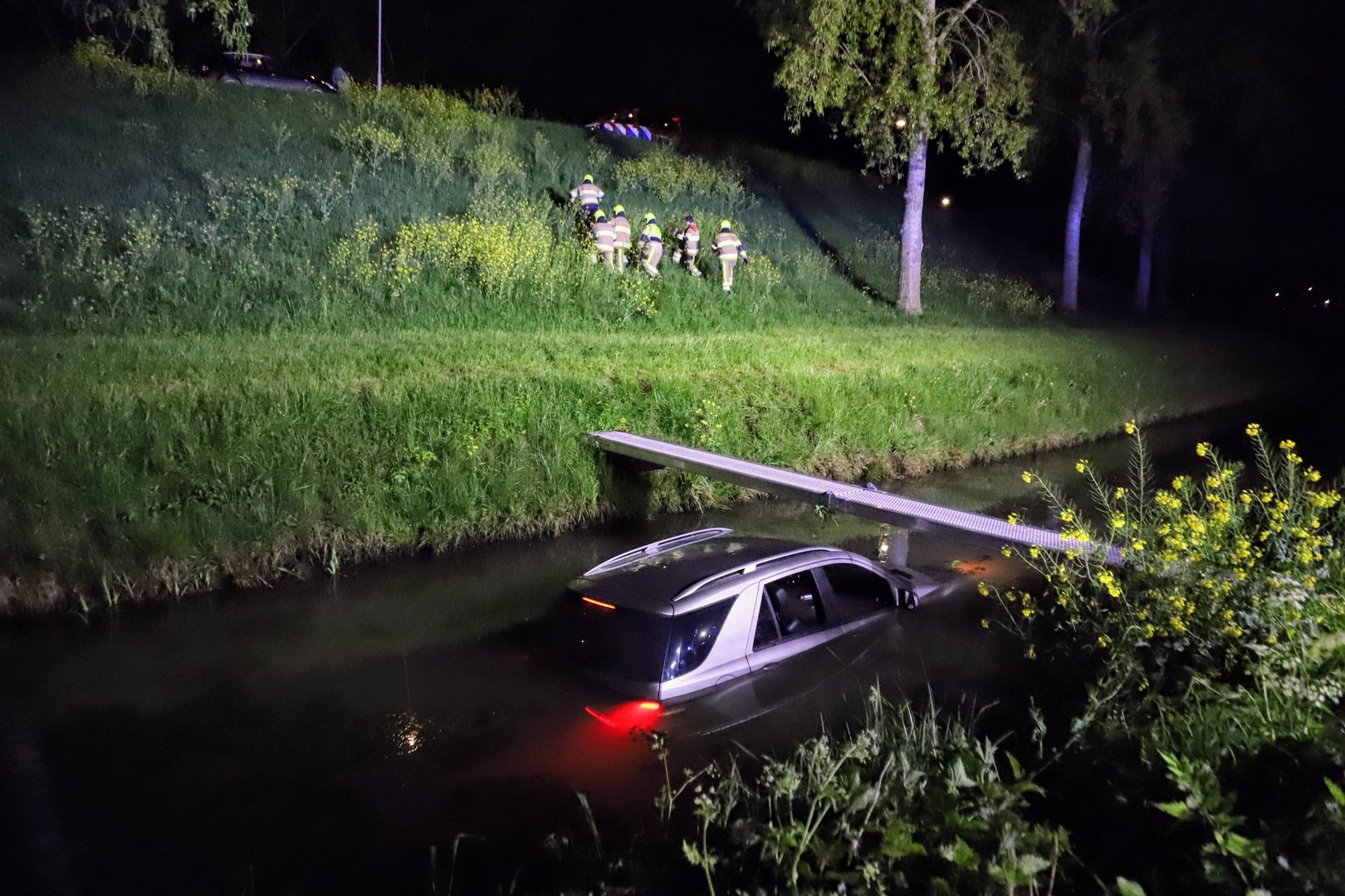 Auto belandt in de sloot, brandweer haalt bestuurder van het dak