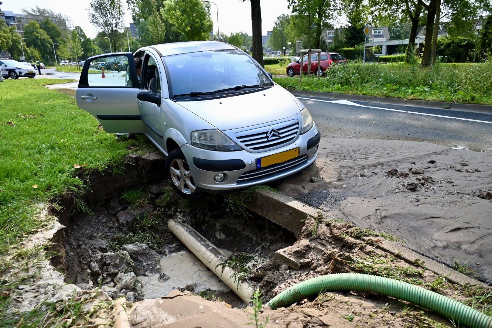 Auto op rand van sinkhole door gesprongen waterleiding