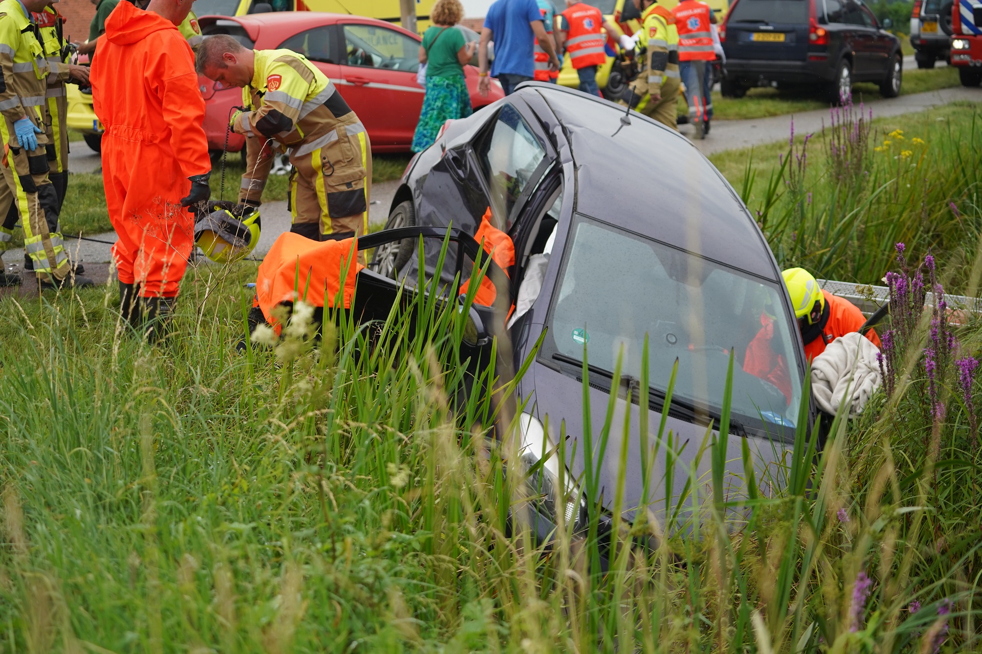 Auto belandt in sloot na aanrijding, bestuurder bekneld