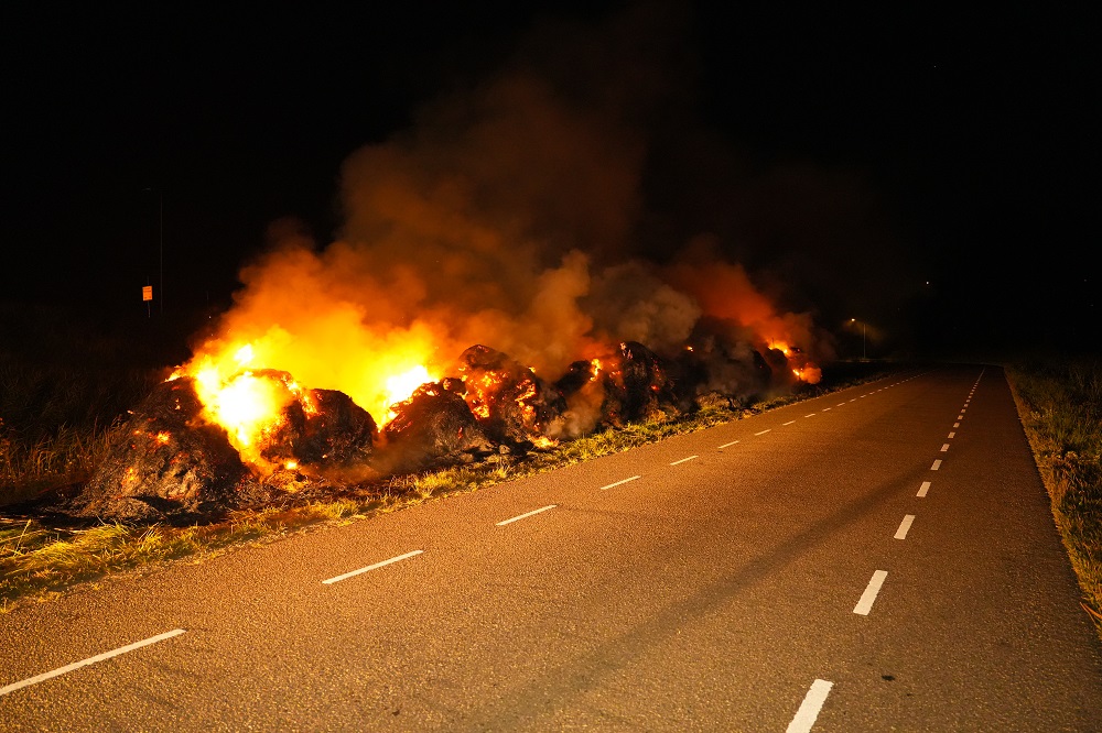 Gemaaid gras en riet vliegt in brand, brandweer druk met blussen