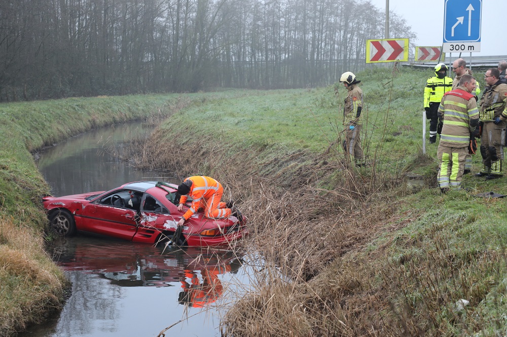 Auto raakt vangrail en belandt in sloot, inzittenden bevrijdt